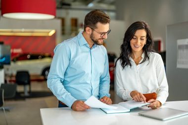 PeakAvenue consulting Two people stand in front of a desk and point to a book