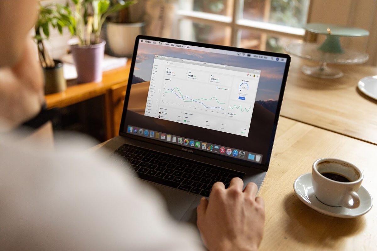 Laptop showing a performance dashboard and a coffee mug standing a table.