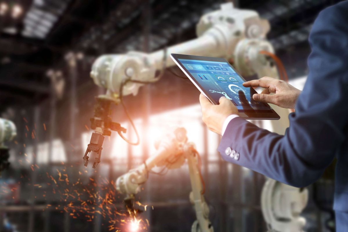 Person standing in production hall working on a tablet.