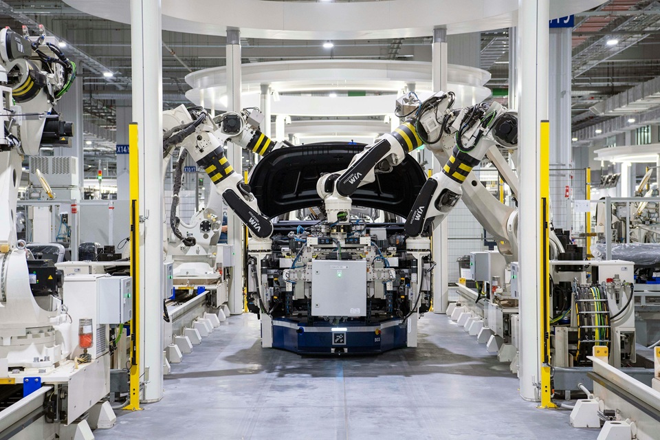 Photo of an assembly hall where robot arms are used to work on a vehicle body